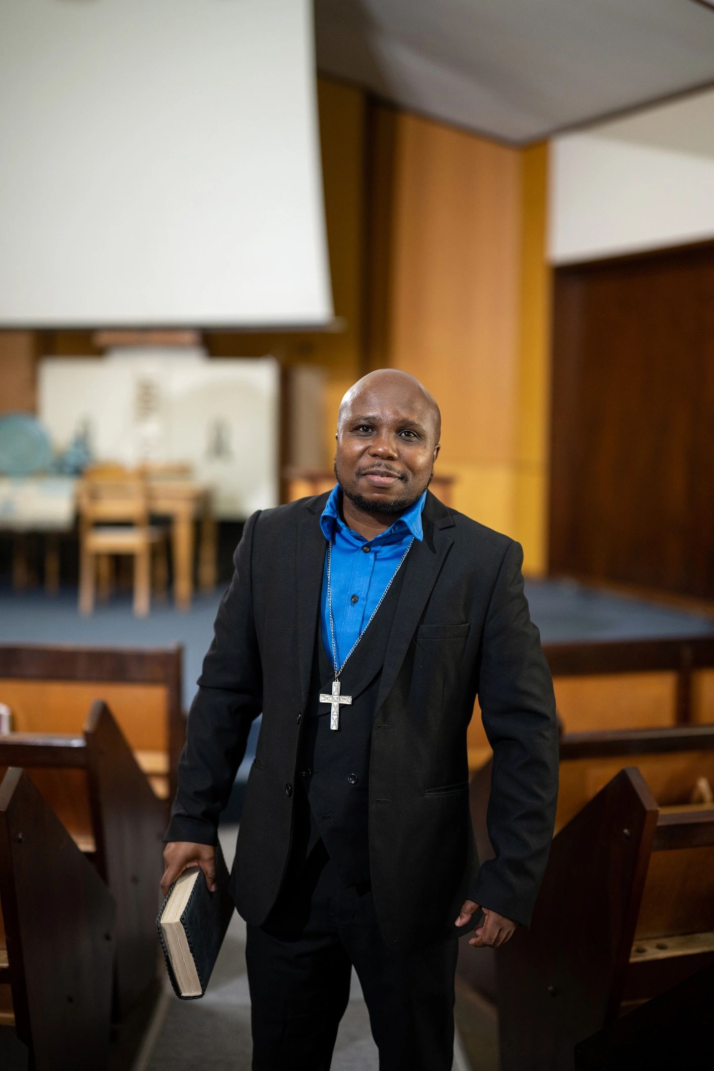 Pastor standing in church holding a Bible